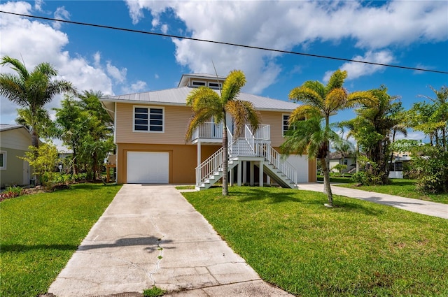 24261 Captain Kidd Blvd, Punta Gorda, FL 33955 - raised beach house featuring stairs, concrete driveway, an attached garage, a porch, and a front yard