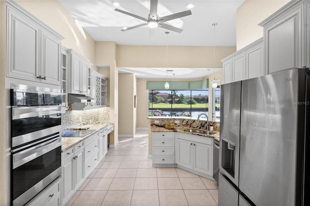 3322 Sandpiper Dr, Punta Gorda, FL 33950 - kitchen with stainless steel appliances, decorative backsplash, a peninsula, a ceiling fan, and light stone countertops