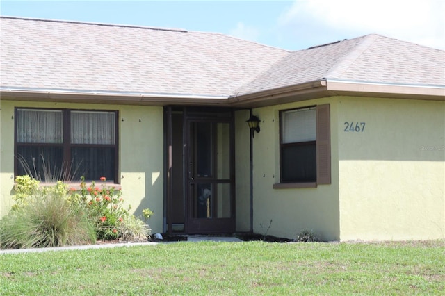2467 Herron Ter, Port Charlotte, FL 33981 - view of exterior entry with a yard, roof with shingles, and stucco siding