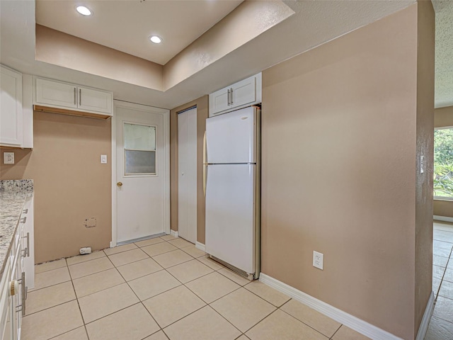 6483 Fabian Rd, North Port, FL 34287 - kitchen featuring freestanding refrigerator, white cabinets, light tile patterned floors, light stone countertops, and recessed lighting