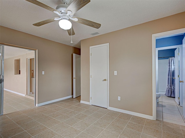 6483 Fabian Rd, North Port, FL 34287 - unfurnished bedroom with light tile patterned floors, ceiling fan, ensuite bath, and a textured ceiling