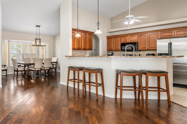 2373 Chartwell Ave, North Port, FL 34288 - kitchen featuring black microwave, stainless steel fridge, a breakfast bar area, backsplash, and dark wood-style flooring