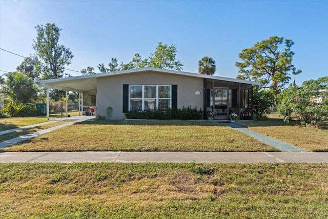 3197 Normandy Dr, Port Charlotte, FL 33952 - view of front facade featuring stucco siding, a front yard, an attached carport, a sunroom, and driveway