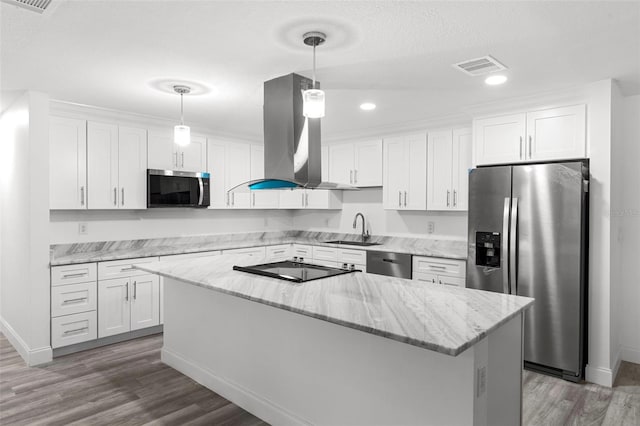 4996 49th St, Vero Beach, FL 32967 - kitchen featuring stainless steel appliances, island range hood, white cabinets, wood finished floors, and a kitchen island