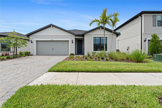 2477 Gabel Oak Dr, North Port, FL 34289 - ranch-style house with an attached garage, decorative driveway, a front lawn, and stucco siding