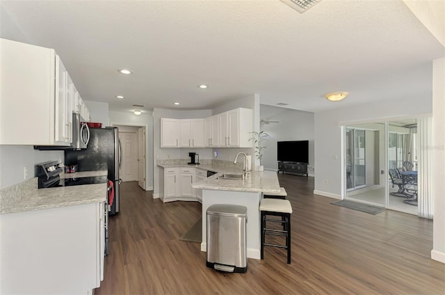 4038 Corydon Ave, North Port, FL 34286 - kitchen featuring appliances with stainless steel finishes, dark wood-style floors, a kitchen breakfast bar, a peninsula, and white cabinetry