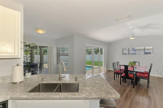 4038 Corydon Ave, North Port, FL 34286 - kitchen featuring wood finished floors, light stone counters, a ceiling fan, vaulted ceiling, and a peninsula