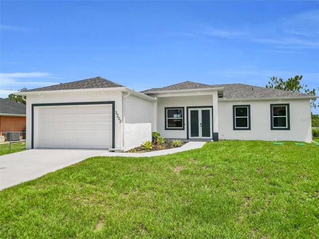3202 41st St W, Lehigh Acres, FL 33971 - view of front of home featuring french doors, stucco siding, a garage, a front lawn, and driveway