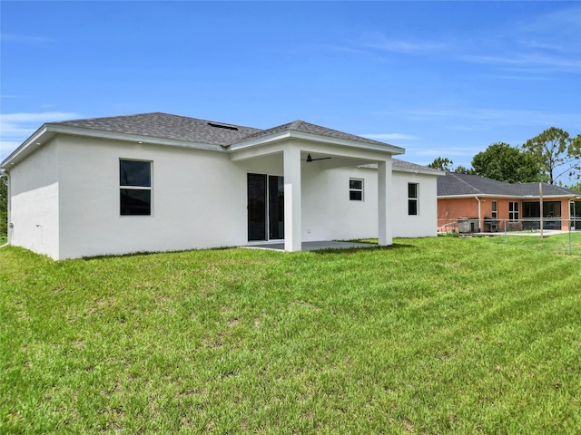 3202 41st St W, Lehigh Acres, FL 33971 - rear view of property featuring ceiling fan, stucco siding, a yard, and roof with shingles