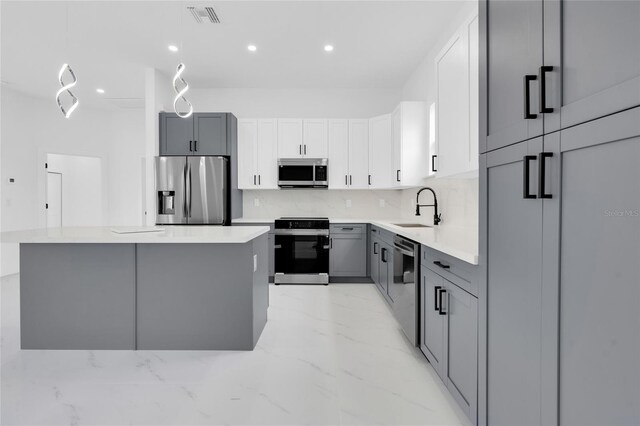 3202 41st St W, Lehigh Acres, FL 33971 - kitchen with stainless steel appliances, light marble finish floors, a kitchen island, gray cabinets, and recessed lighting