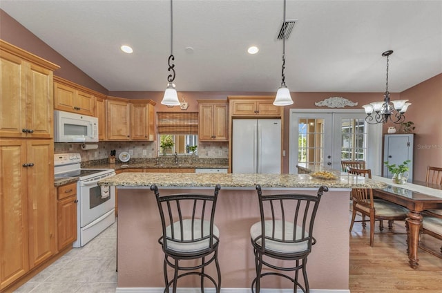 3305 Nansen Ln, North Port, FL 34286 - kitchen with white appliances, french doors, a kitchen island, a breakfast bar area, and recessed lighting