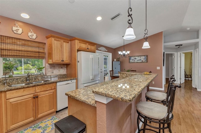 3305 Nansen Ln, North Port, FL 34286 - kitchen with white appliances, lofted ceiling, a breakfast bar, a center island, and light stone counters