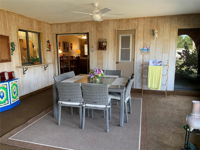 21460 Sheldon Ave, Port Charlotte, FL 33952 - dining room featuring wooden walls, a ceiling fan, and carpet flooring
