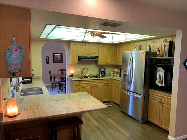 21460 Sheldon Ave, Port Charlotte, FL 33952 - kitchen featuring black appliances, exhaust hood, wood finished floors, arched walkways, and a peninsula