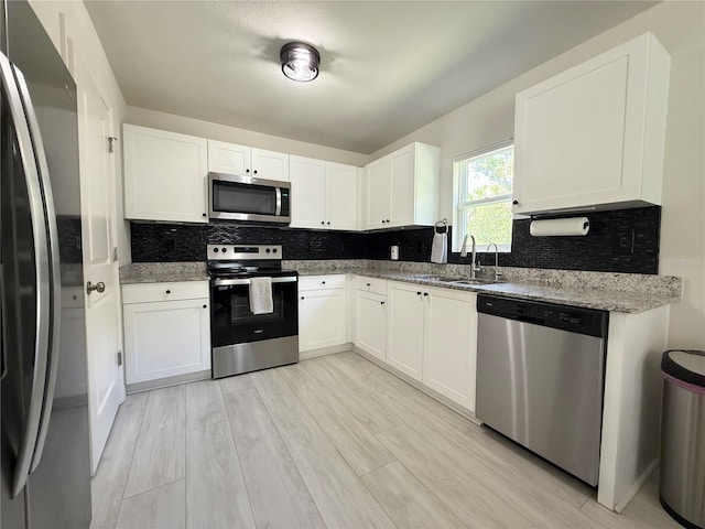 17344 York Ave, Port Charlotte, FL 33948 - kitchen with stainless steel appliances, backsplash, white cabinets, and light wood-style flooring