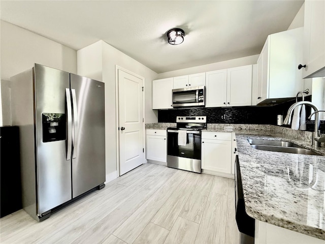 17344 York Ave, Port Charlotte, FL 33948 - kitchen featuring appliances with stainless steel finishes, light stone counters, white cabinetry, light wood-style floors, and tasteful backsplash