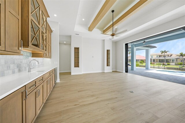 2815 Coral Way, Punta Gorda, FL 33950 - kitchen featuring a ceiling fan, backsplash, glass insert cabinets, brown cabinets, and light wood-style flooring