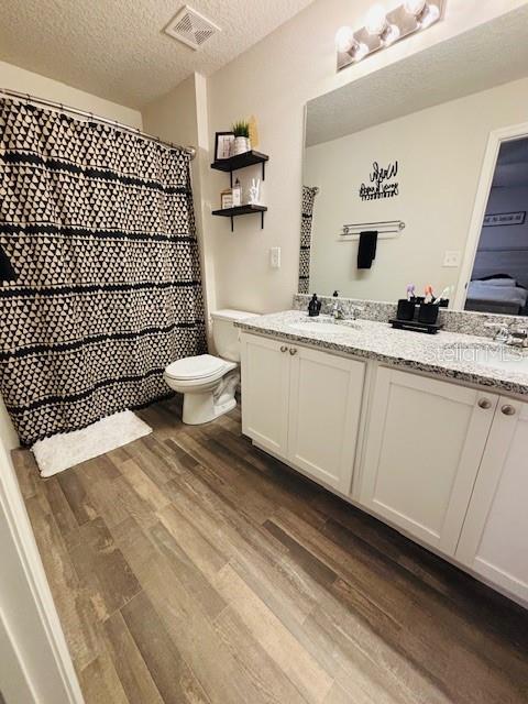 6766 N Pavilion Loop, Citrus Springs, FL 34433 - bathroom featuring wood finished floors, double vanity, a textured ceiling, and a shower with curtain