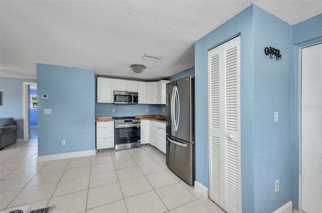 25082 Harborview Rd, Punta Gorda, FL 33980 - kitchen with appliances with stainless steel finishes, white cabinets, light tile patterned floors, a textured ceiling, and a textured wall
