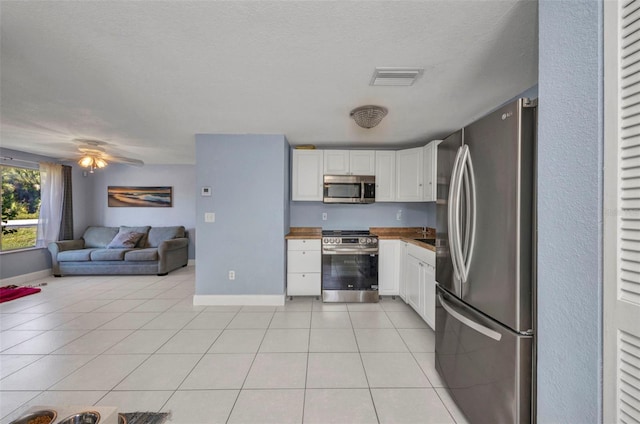 25082 Harborview Rd, Punta Gorda, FL 33980 - kitchen with stainless steel appliances, white cabinets, light tile patterned floors, open floor plan, and a textured ceiling
