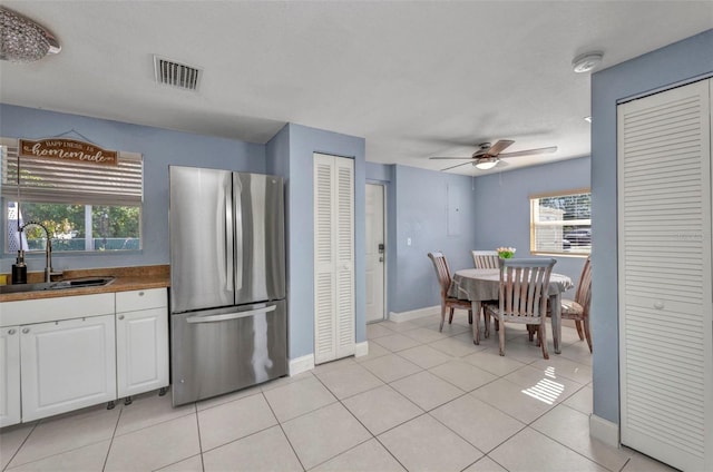 25082 Harborview Rd, Punta Gorda, FL 33980 - kitchen with freestanding refrigerator, white cabinets, ceiling fan, and light tile patterned flooring