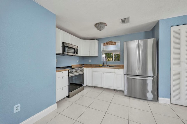 25082 Harborview Rd, Punta Gorda, FL 33980 - kitchen featuring appliances with stainless steel finishes, white cabinetry, a textured wall, and light tile patterned floors