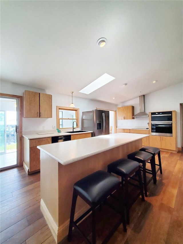 3456 Highlands Rd, Punta Gorda, FL 33983 - kitchen with wall chimney exhaust hood, stainless steel appliances, a skylight, light wood-type flooring, and light countertops