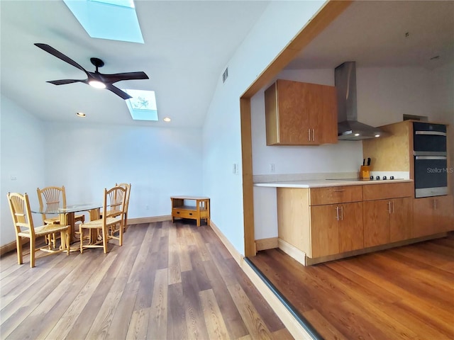 3456 Highlands Rd, Punta Gorda, FL 33983 - kitchen featuring a skylight, wall chimney exhaust hood, oven, light countertops, and light wood finished floors