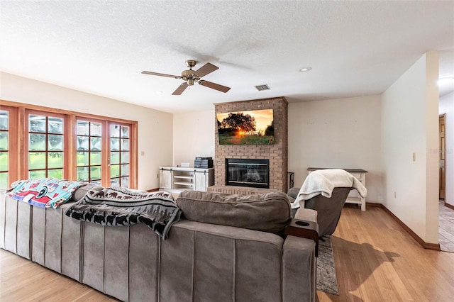 2788 SW County Road 769, Arcadia, FL 34266 - living room featuring light wood-type flooring, a brick fireplace, ceiling fan, and a textured ceiling
