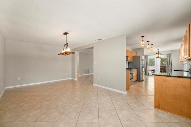 10810 Wheeler Pl, Punta Gorda, FL 33950 - kitchen featuring stainless steel appliances, light tile patterned floors, pendant lighting, brown cabinetry, and a chandelier
