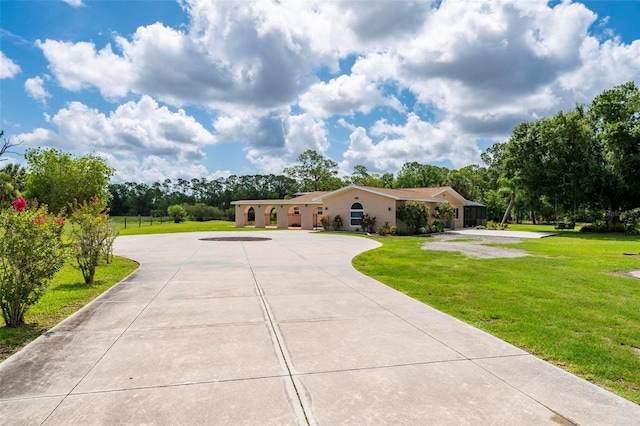 10810 Wheeler Pl, Punta Gorda, FL 33950 - view of front of property with curved driveway, a front yard, stucco siding, and view of wooded area
