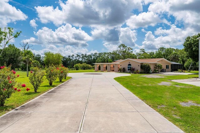 10810 Wheeler Pl, Punta Gorda, FL 33950 - view of front of property featuring curved driveway, a front lawn, and view of scattered trees