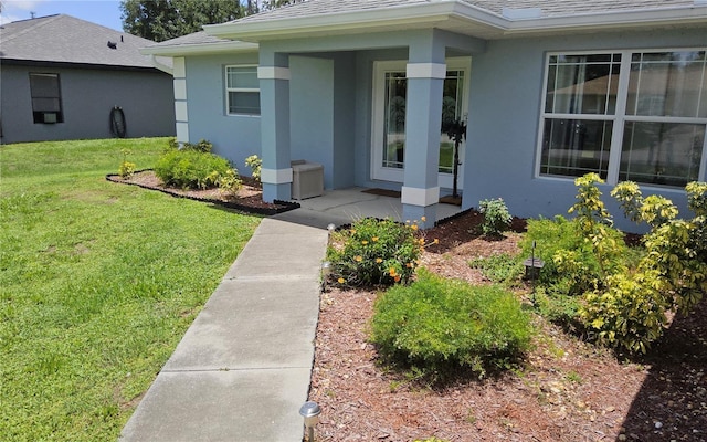 6341 Opa Locka Ln, North Port, FL 34291 - view of exterior entry with stucco siding, a yard, a shingled roof, and covered porch