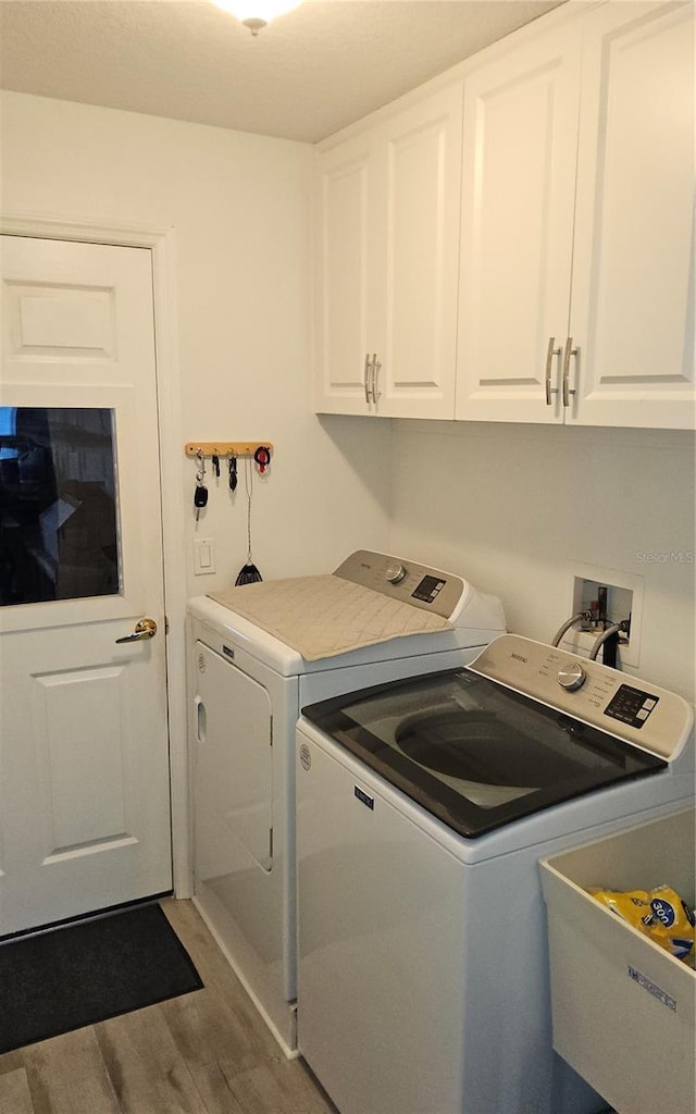 6341 Opa Locka Ln, North Port, FL 34291 - washroom featuring separate washer and dryer, wood finished floors, and cabinet space