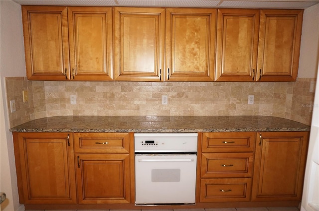 1128 Rum Cay Ct, Punta Gorda, FL 33950 - kitchen with brown cabinetry, dark stone countertops, oven, and tasteful backsplash