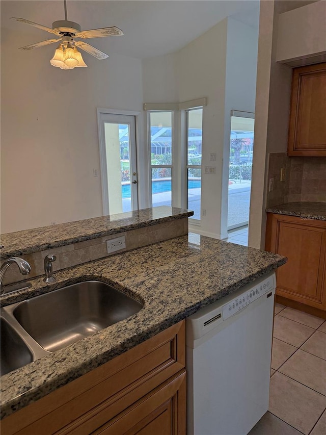 1128 Rum Cay Ct, Punta Gorda, FL 33950 - kitchen featuring dishwasher, brown cabinetry, backsplash, and dark stone countertops