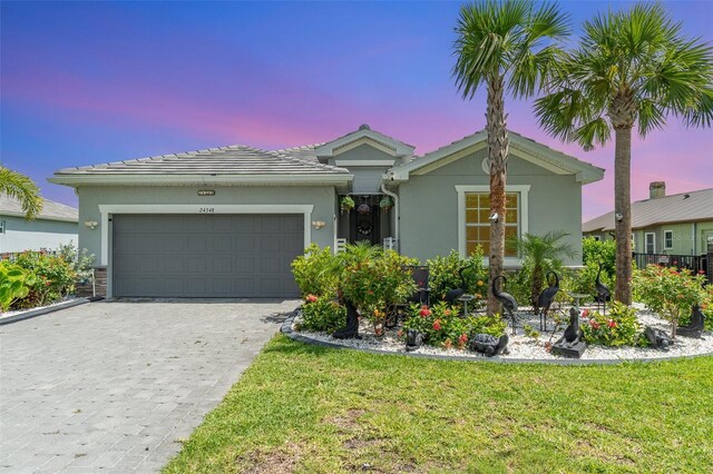 24348 Nicobar Ln, Punta Gorda, FL 33955 - single story home with stucco siding, an attached garage, decorative driveway, and a front yard