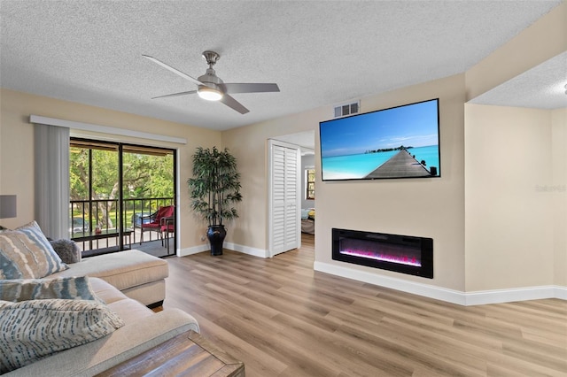 19505 Quesada Ave Unit Vv201, Port Charlotte, FL 33948 - living room featuring light wood finished floors, a textured ceiling, ceiling fan, and a glass covered fireplace