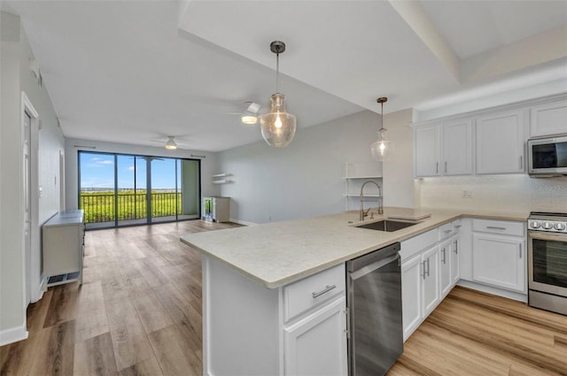 900 E Marion Ave Unit 1203, Punta Gorda, FL 33950 - kitchen with stainless steel appliances, a peninsula, tasteful backsplash, decorative light fixtures, and light wood-style flooring