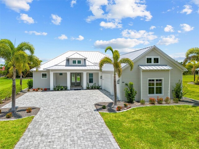 28960 Gin Ln, Punta Gorda, FL 33982 - modern farmhouse featuring decorative driveway, a standing seam roof, an attached garage, and a front lawn