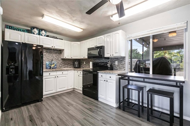 8513 Heister St, Punta Gorda, FL 33982 - kitchen featuring black appliances, tasteful backsplash, wood finished floors, a ceiling fan, and white cabinets