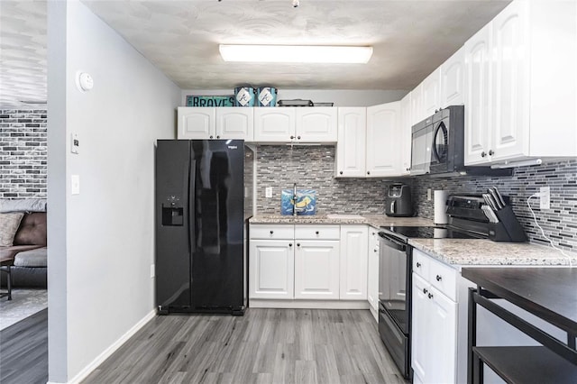8513 Heister St, Punta Gorda, FL 33982 - kitchen with black appliances, light wood finished floors, backsplash, and white cabinetry