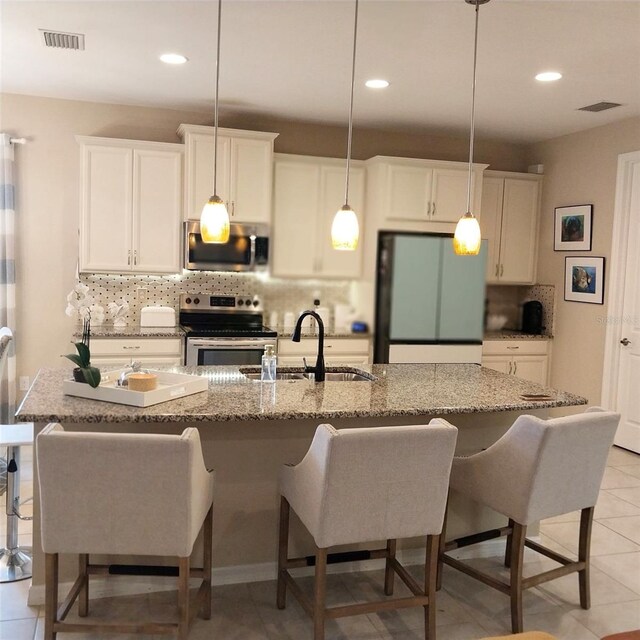25224 Lahore Ln, Punta Gorda, FL 33983 - kitchen featuring appliances with stainless steel finishes, backsplash, recessed lighting, a kitchen island with sink, and a kitchen breakfast bar