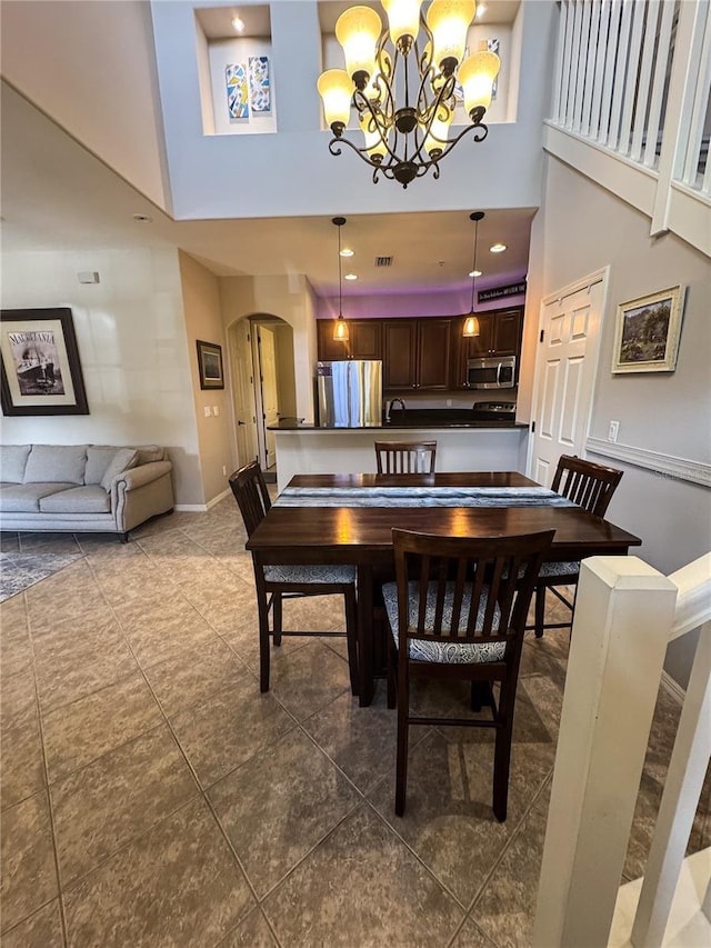 11220 Paseo Grande Blvd Unit 5207, Fort Myers, FL 33912 - dining room with arched walkways, a towering ceiling, a chandelier, and dark tile patterned flooring