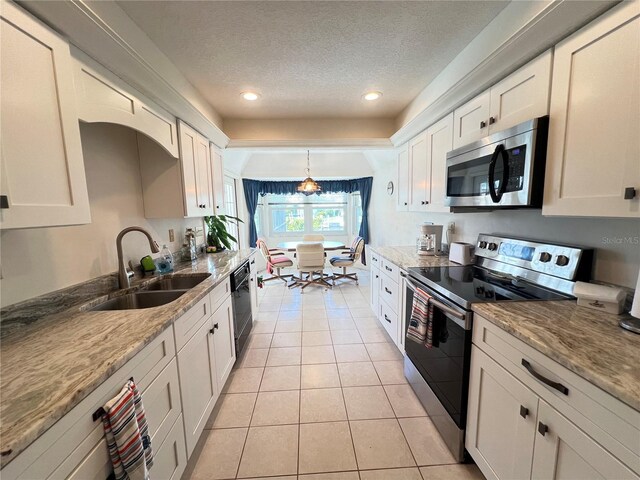 2526 Brazilia Ct, Punta Gorda, FL 33950 - kitchen with appliances with stainless steel finishes, light tile patterned flooring, a textured ceiling, white cabinets, and light stone counters