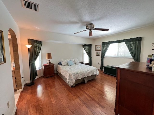 2526 Brazilia Ct, Punta Gorda, FL 33950 - bedroom with arched walkways, light wood-type flooring, a textured ceiling, and a ceiling fan