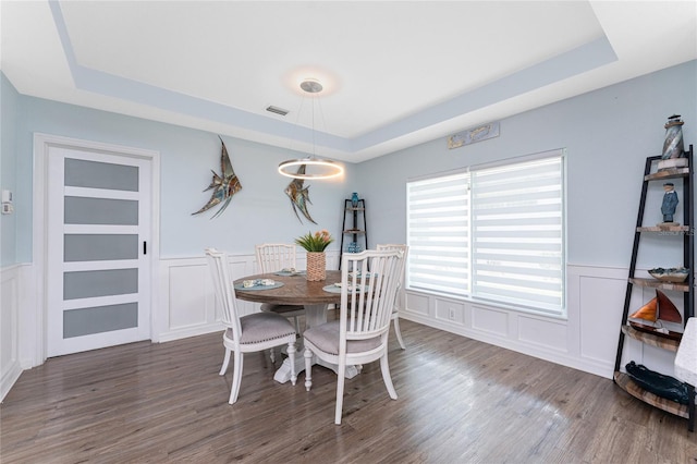 26254 Stillwater Cir, Punta Gorda, FL 33955 - dining room featuring a tray ceiling, a decorative wall, wood finished floors, and wainscoting
