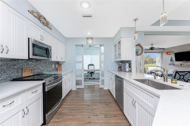 26254 Stillwater Cir, Punta Gorda, FL 33955 - kitchen featuring a ceiling fan, appliances with stainless steel finishes, backsplash, white cabinets, and light wood-style flooring
