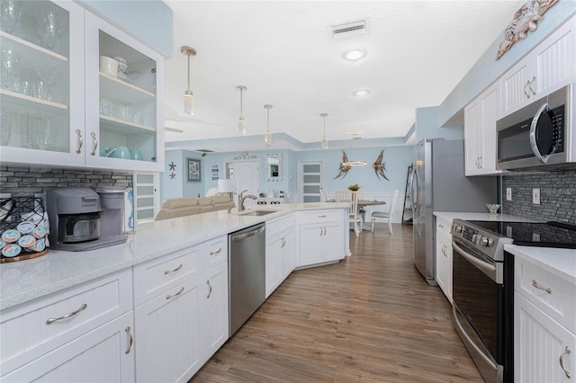26254 Stillwater Cir, Punta Gorda, FL 33955 - kitchen with stainless steel appliances, white cabinets, tasteful backsplash, glass insert cabinets, and decorative light fixtures