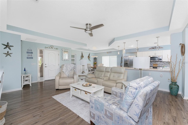 26254 Stillwater Cir, Punta Gorda, FL 33955 - living room featuring a raised ceiling, a ceiling fan, and dark wood-type flooring